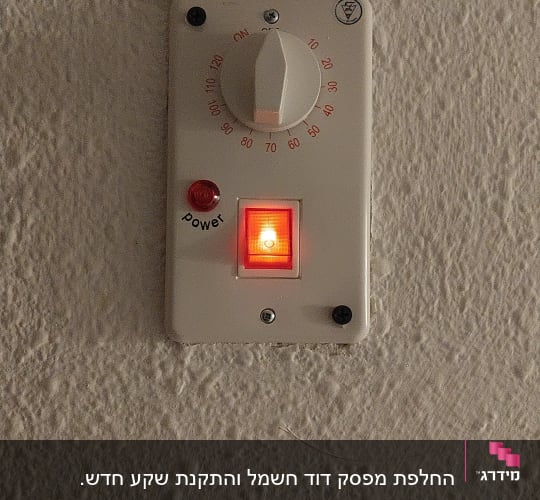תרמוסטט עם כפתור אדום מואר על קיר